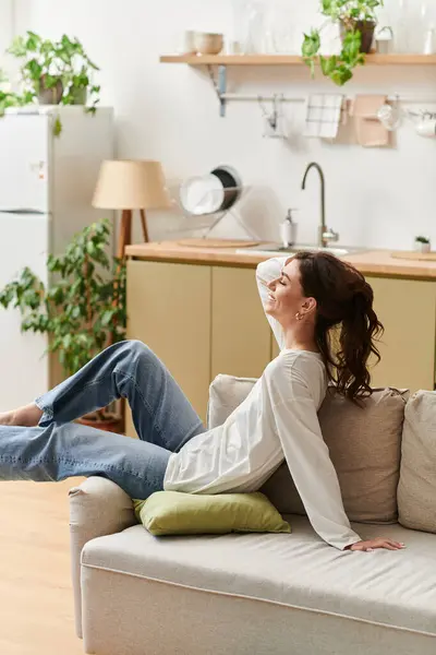 A young woman relaxes on her couch, savoring a peaceful moment in her chic apartment. — Stock Photo
