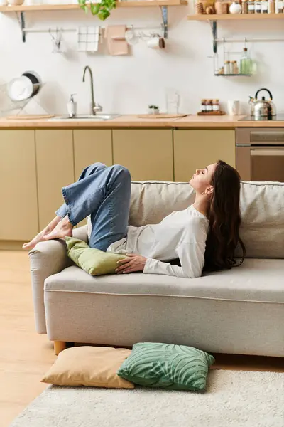 Relaxing comfortably on the sofa, a young woman enjoys a peaceful moment at home. — Stock Photo