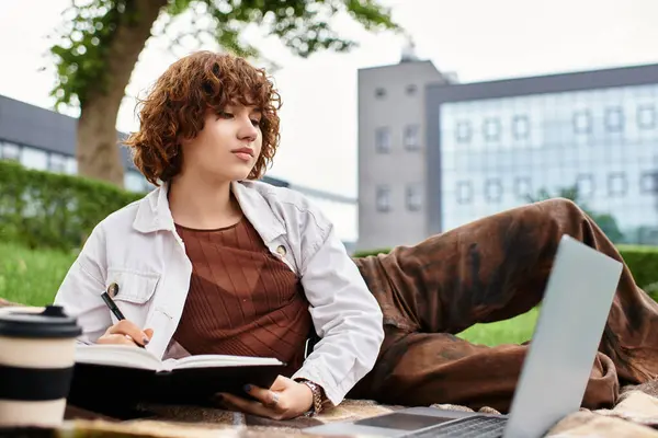 Curly-haired woman engages in freelance work outdoors, surrounded by lush greenery. — Stock Photo