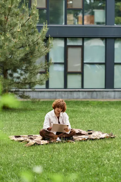Curly haired woman focuses on her tasks while seated on a blanket in a sunny park. — Stock Photo