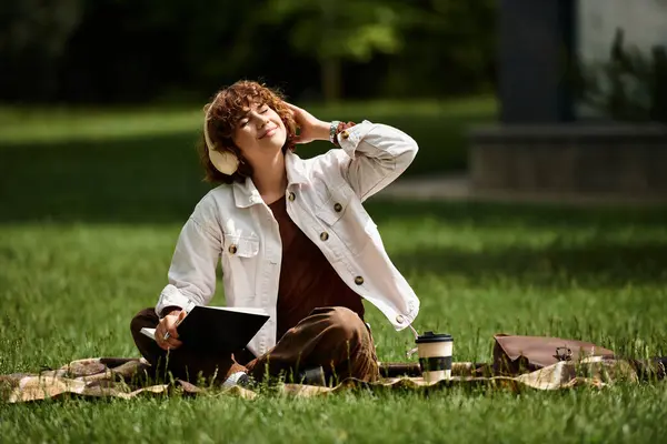 Curls frame her face as she enjoys a sunny day on a blanket in a serene park, absorbing nature. — Stock Photo