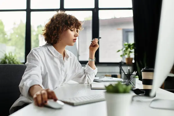 A young businesswoman with curly hair is concentrating while working at her desk. — Stock Photo