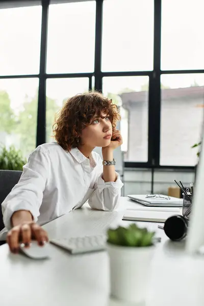 Curly-haired businesswoman ponders deeply at her desk in a modern office. — Stock Photo