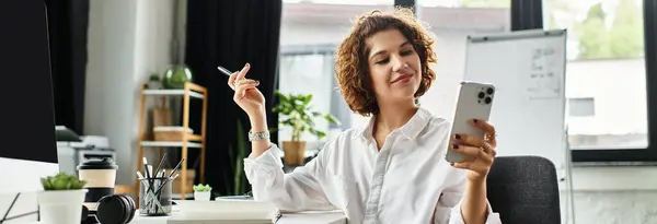 Curly-haired businesswoman enjoys her workday while using her smartphone at a stylish office, banner — Stock Photo