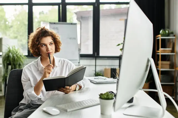 In a stylish office, a thoughtful young businesswoman reviews her notes while working diligently. — Stock Photo