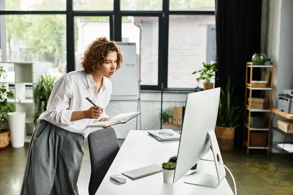 A young businesswoman with curly hair focuses on her notes while working at a desk. — Stock Photo