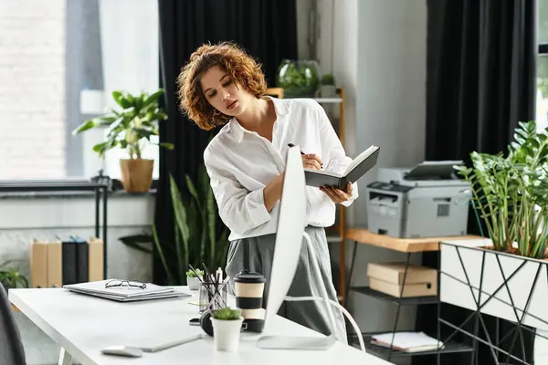A young woman with curly hair engages in work at a stylish office, focused on her notes. — Stock Photo
