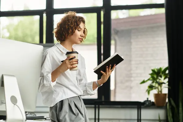 Young businesswoman with curly hair reflects on her reading while sipping coffee in the office. — Stock Photo