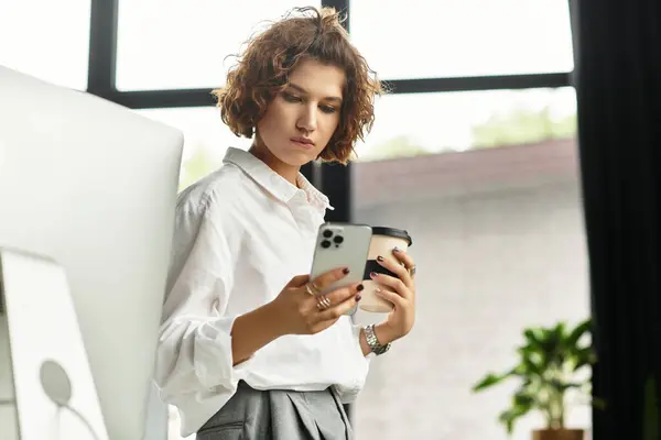 Young businesswoman with curly hair checks her phone while holding a cup of coffee in summer. — Stock Photo
