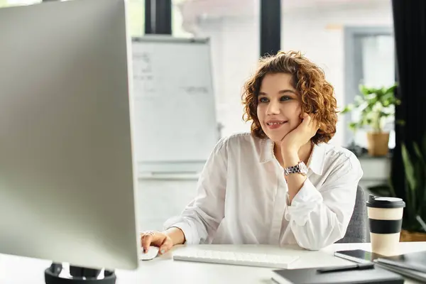 A young businesswoman with curly hair engages with her computer while working in a stylish office. — Stock Photo