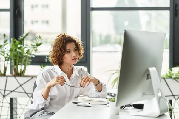 A young businesswoman with curly hair analyzes her work in a stylish office setting. — Stock Photo