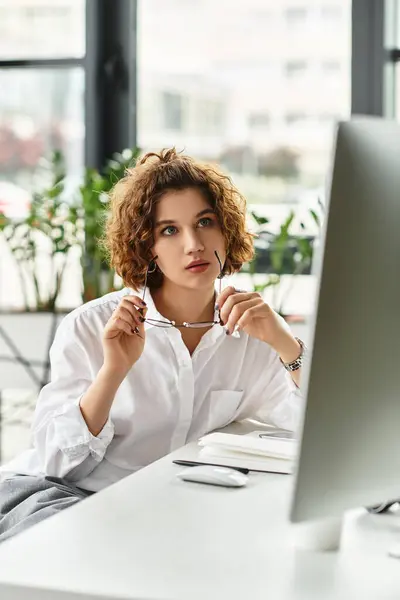 A young businesswoman with curly hair thoughtfully reviews tasks in a sleek office environment. — Stock Photo