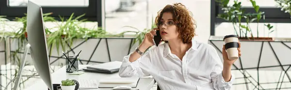 A young woman with curly hair talks on the phone while holding coffee, engaged in work, banner — Stock Photo