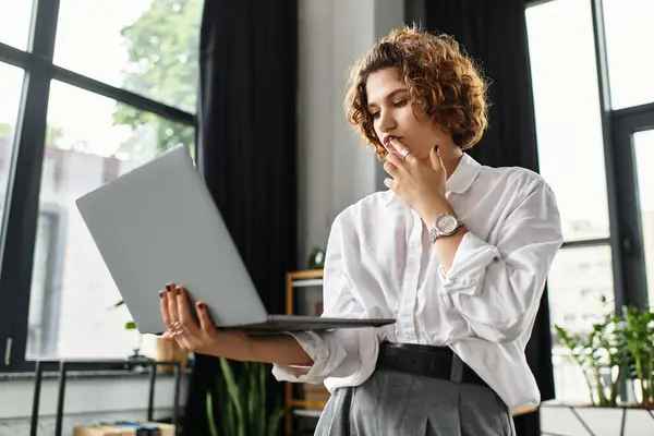 A young professional with curly hair engages deeply with her laptop while working. — Stock Photo