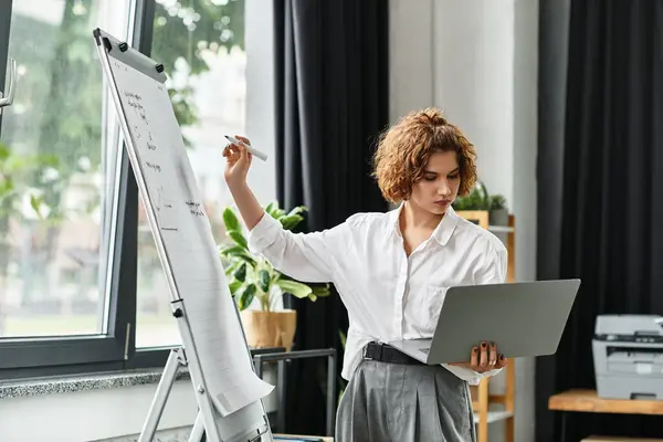 Curly-haired businesswoman collaborates in a bright office, balancing a laptop and notes. — Stock Photo