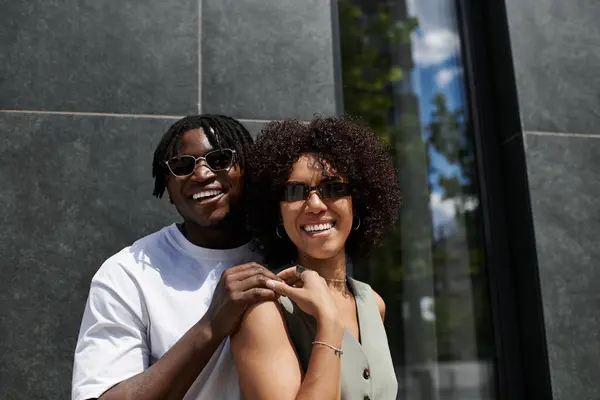 Una joven pareja afroamericana comparte un momento alegre mientras explora la ciudad en un día soleado. - foto de stock