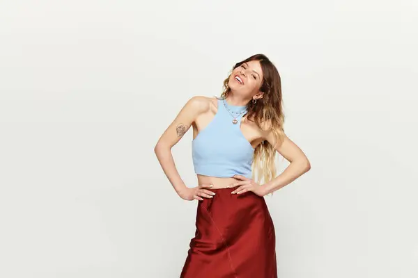 A young woman exudes confidence in a light blue top and flowing skirt, smiling brightly. — Stock Photo