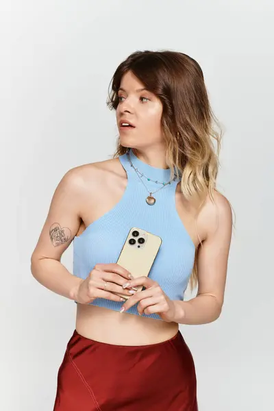 Beautiful young woman stands with a casual expression, enjoying summer while holding her phone. — Stock Photo