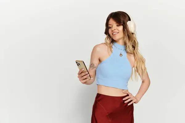 Enthusiastic young woman in a vibrant outfit interacts with her smartphone while wearing headphones. — Stock Photo