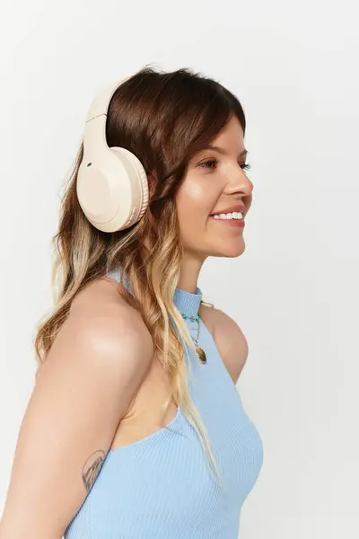 Joyful young woman in a blue outfit smiles in stylish headphones, radiating summer vibes. — Stock Photo