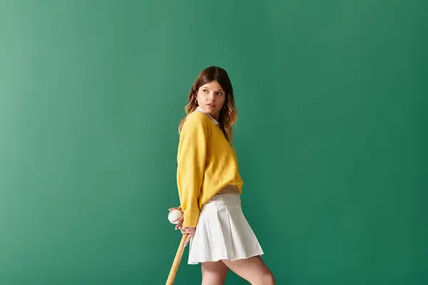 A young woman in a bright yellow sweater and white skirt strikes a playful summer pose. — Stock Photo