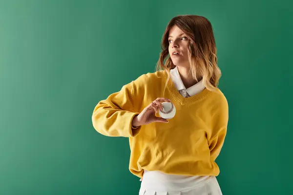 A lovely woman poses with a playful object against a vibrant green backdrop, exuding joy. — Stock Photo