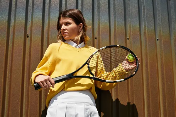 Young woman in a vibrant yellow sweater holds a tennis racket, exuding summer energy and excitement. — Stock Photo