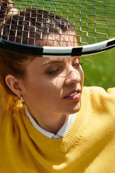 A young beautiful woman enjoys a sunny afternoon, holding a tennis racket while smiling gently. — Stock Photo