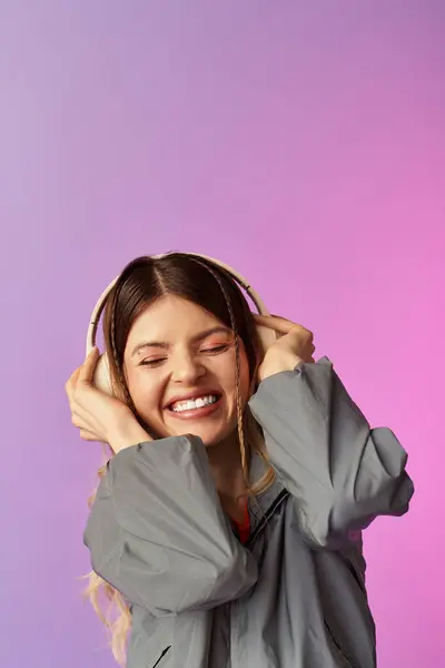 Giovane donna in abbigliamento casual esprime pura gioia mentre ascolta musica su uno sfondo colorato — Foto stock