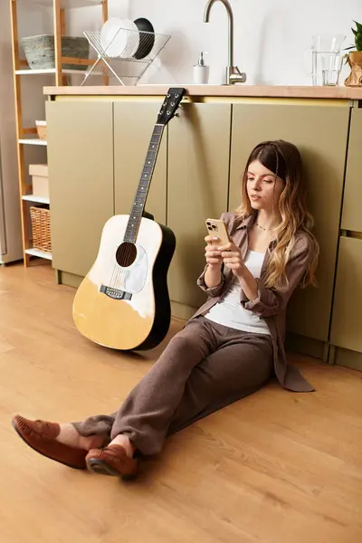 Une belle jeune femme s'engage avec son téléphone, entourée d'une atmosphère chaleureuse et invitante. — Photo de stock
