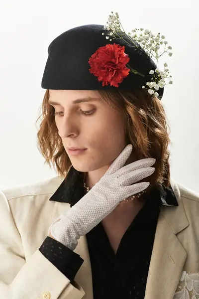 A stylish young man in a floral hat poses thoughtfully in a chic outfit. — Stock Photo