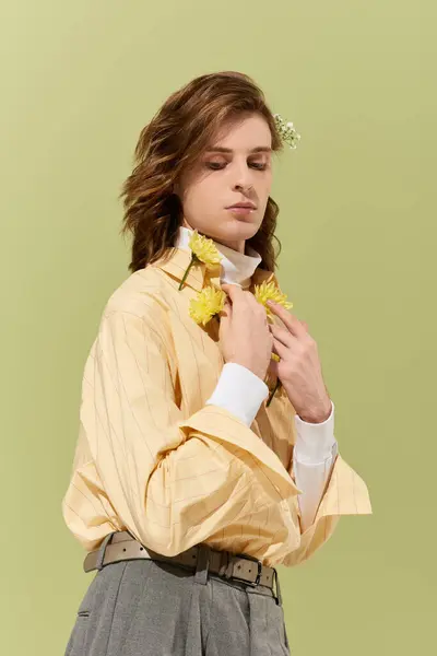 Стильний молодий чоловік граціозно позує, виділяючи сучасне вбрання, прикрашене квітами. — стокове фото