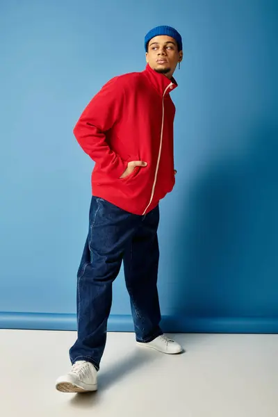 Un giovane nero elegante in una giacca rossa e berretto posa con fiducia. — Foto stock