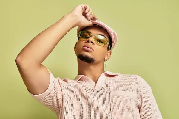 A stylish young man confidently poses in a pink polo and flat cap, showcasing modern fashion. — Stock Photo