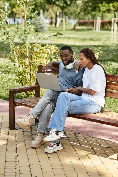 Coppia condivide sorrisi e risate insieme mentre si gode il tempo su un computer portatile all'aperto. — Foto stock