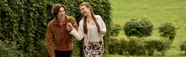 Любящие пары идут рука об руку, разделяя смех и счастье в спокойной обстановке на открытом воздухе. — стоковое фото