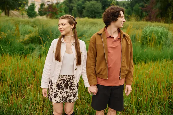 Любящая пара идет рука об руку, улыбаясь, исследуя пышную растительность в парке. — стоковое фото