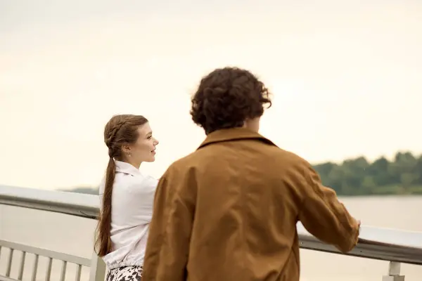 Casal amoroso caminha lado a lado, compartilhando sorrisos e risos perto da margem do rio ao entardecer. — Fotografia de Stock