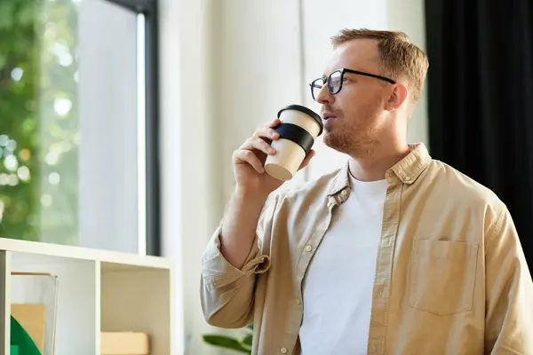 Хорошо одетый молодой человек наслаждается кофе, глядя в окно.. — стоковое фото