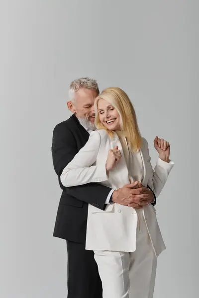 A joyful senior couple shares a warm embrace in stylish outfits. — Stock Photo