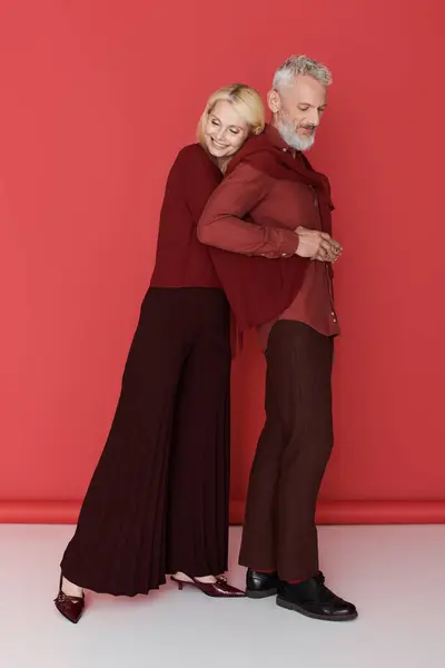 Un couple de personnes âgées joyeux partage une étreinte chaleureuse, exsudant l'amour et le style dans des tenues frappantes. — Photo de stock