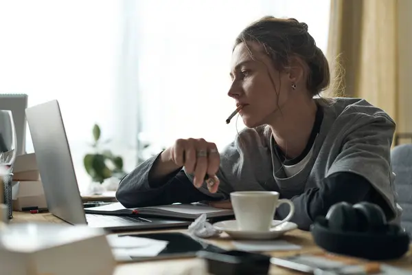Em uma casa aconchegante, uma jovem mulher olha para seu laptop, perdida no pensamento e sentindo-se para baixo. — Fotografia de Stock