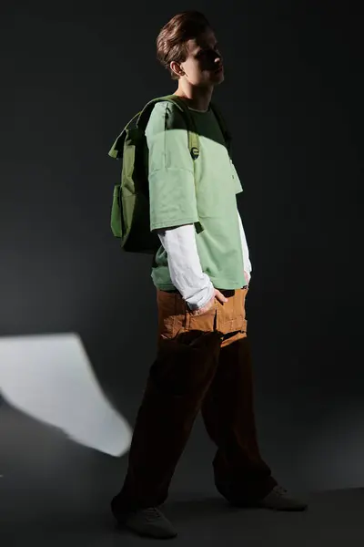 Un adolescente de moda se encuentra con confianza en un espacio débilmente iluminado, encarnando la cultura juvenil moderna. — Stock Photo