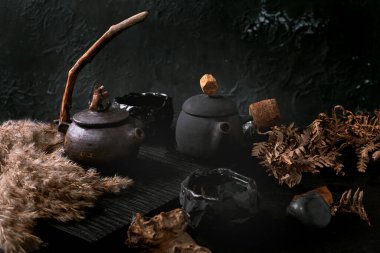 Çin Çay Seremonisi. İki geleneksel seramik siyah çaydanlık. Koyu çay masasında ahşap saplı. Sonbahar havası. Seramik çay fincanları ve kurumuş kamış çiçekleri yan yana..