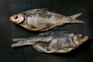 Koyu desenli arka planda kurutulmuş güneşte kurutulmuş deniz balığı. Tuzlu geleneksel aperatif. Deniz ürünleri geçmişi