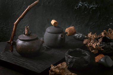 Çin Çay Seremonisi. İki geleneksel seramik siyah çaydanlık. Koyu çay masasında ahşap saplı. Sonbahar havası. Seramik çay fincanları ve kurumuş kamış çiçekleri yan yana..