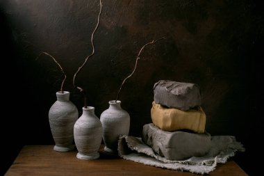Yığınla farklı renkte üç parça ham kil. Gri ve sarı da dahil. Koyu arkaplanlı ahşap bir masa üzerinde. Seramik malzeme mağazaları ve çömlek atölyeleri için bir konsept. Boşluğu kopyala