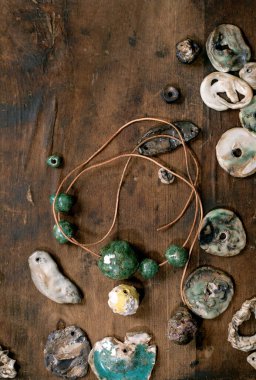 Çeşitli şekiller ve renkler el yapımı seramik boncuklar. Hobi, mücevher montajı, mücevher. Atölye fikri. Koyu ahşap arkaplan, üst manzara.