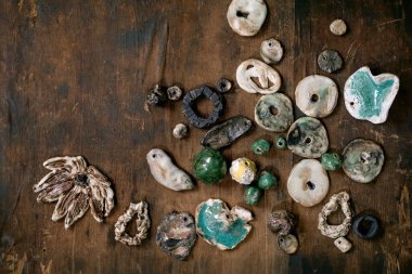 Çeşitli el yapımı seramik boncuklar. Hobi, mücevher montajı, mücevher. Atölye fikri. Koyu tahta arkaplan, üst görünüm, kopyalama alanı