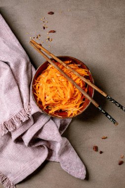 Kore ve Asya mutfağı tabağı: sarımsaklı havuç ve sebze salatası. Seramik kasede yemek çubuklarıyla servis ediliyor. Mocha Mousse tonları masasında küçük kâselerde tatlandırılmış. Sağlıklı beslenme. Üst görünüm